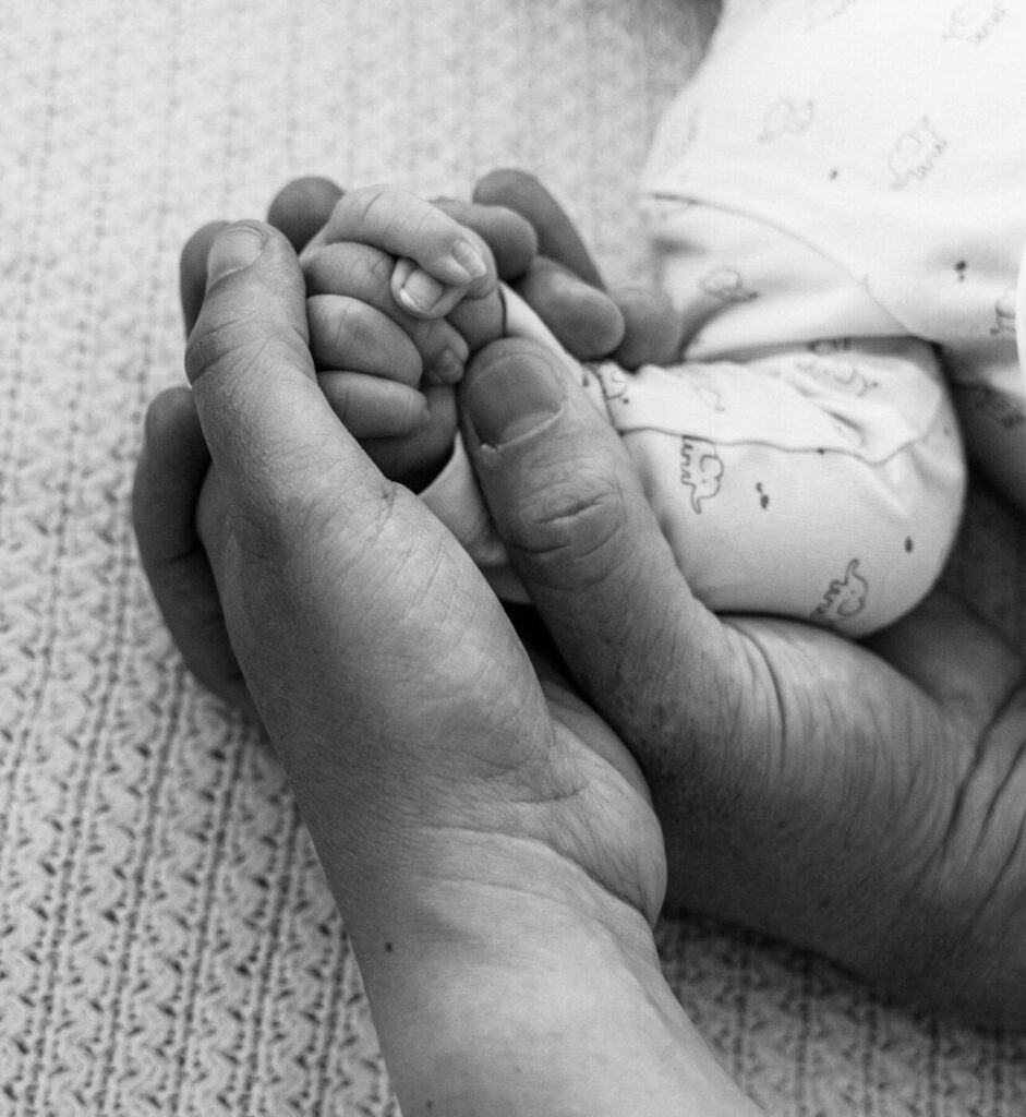 Petits pieds de nouveau-né tenus par ses parents, photographe naissance dans le canton de Vaud